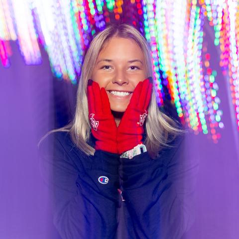 Student posing in front of the Christmas lights